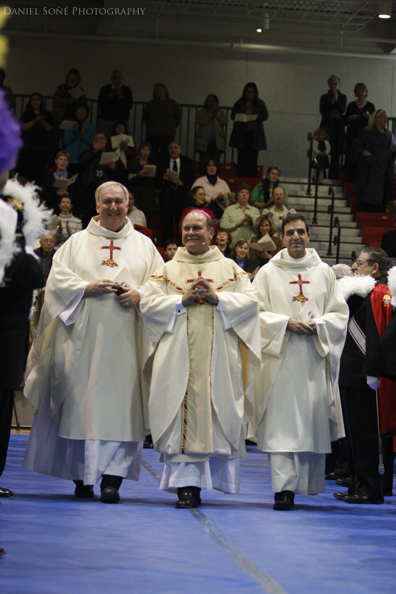 Bishop-elect Fernando Isern, center, processes into the Massari Arena flanked by his ceremonial assistants, Father Richard Mullen, left, and Monsignor Michael Souckar, right.